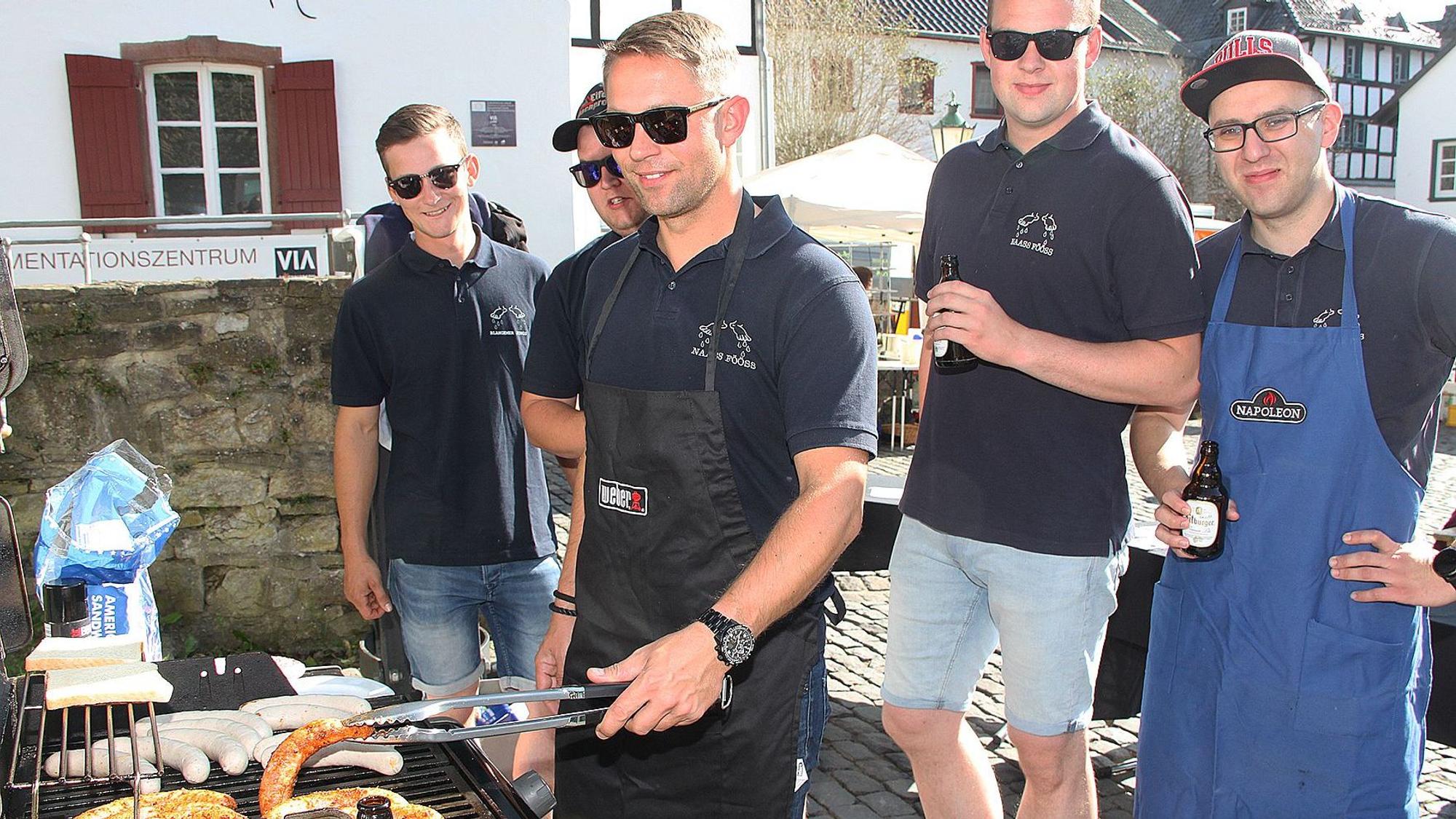 Das Bild zeigt fünf Männer, die hinter einem Grill stehen.