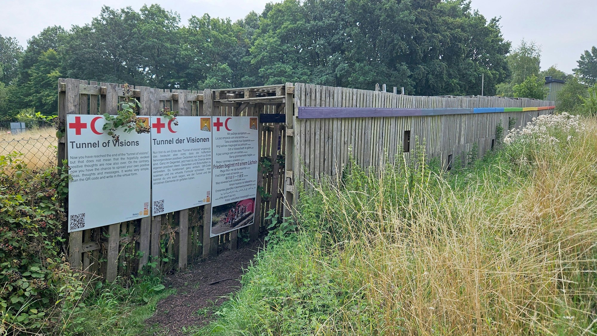 Aus Paletten ist ein Tunnel gebaut, Schilder am Eingang erklären den Sinn.