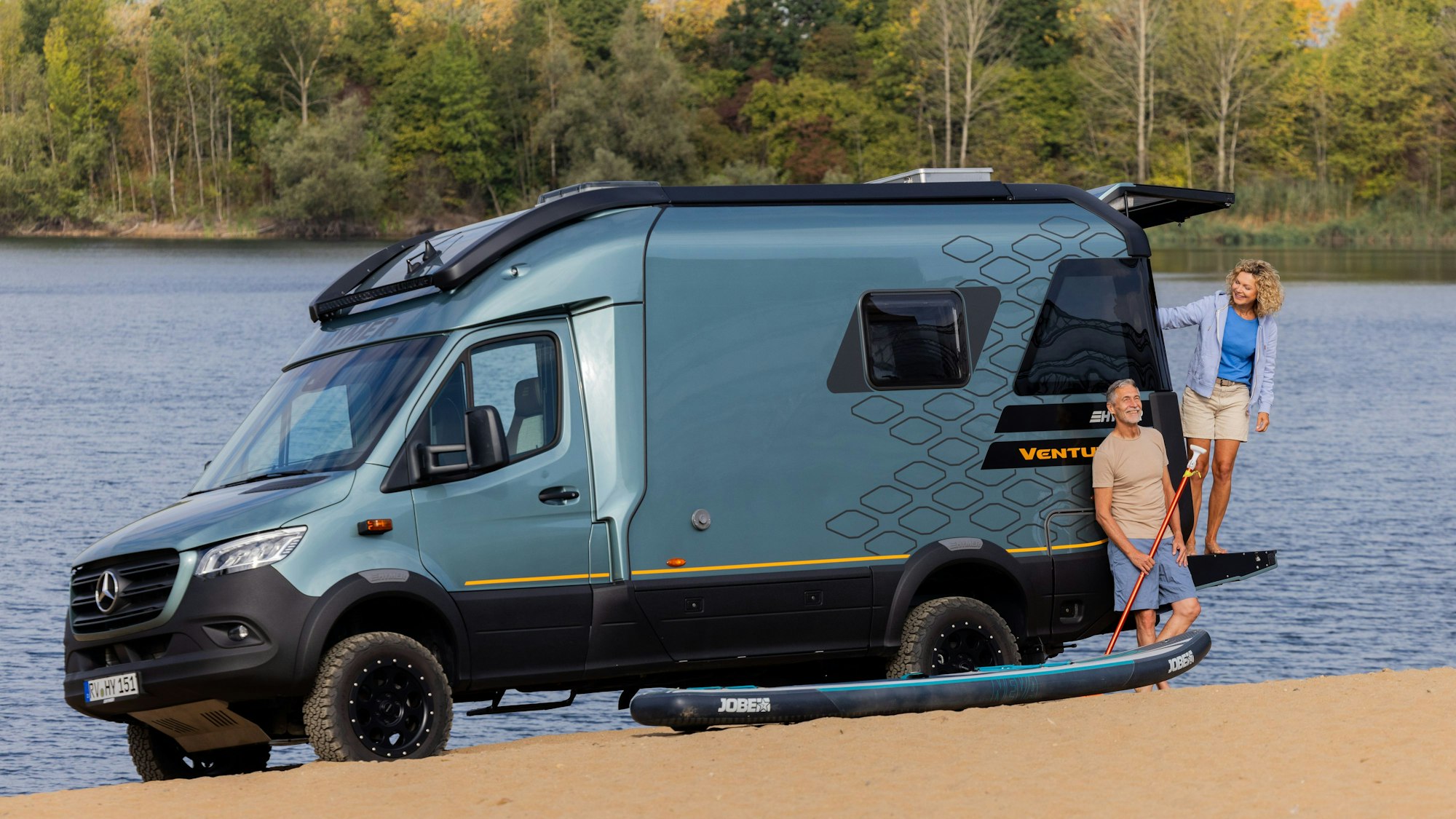 Die Models Anja und Andreas stehen bei einer Pressekonferenz vor dem Caravan Salon am Sandhofsee in dem Offroad-Van Hymer Venture S mit Sonnenterrasse in Yachtoptik.