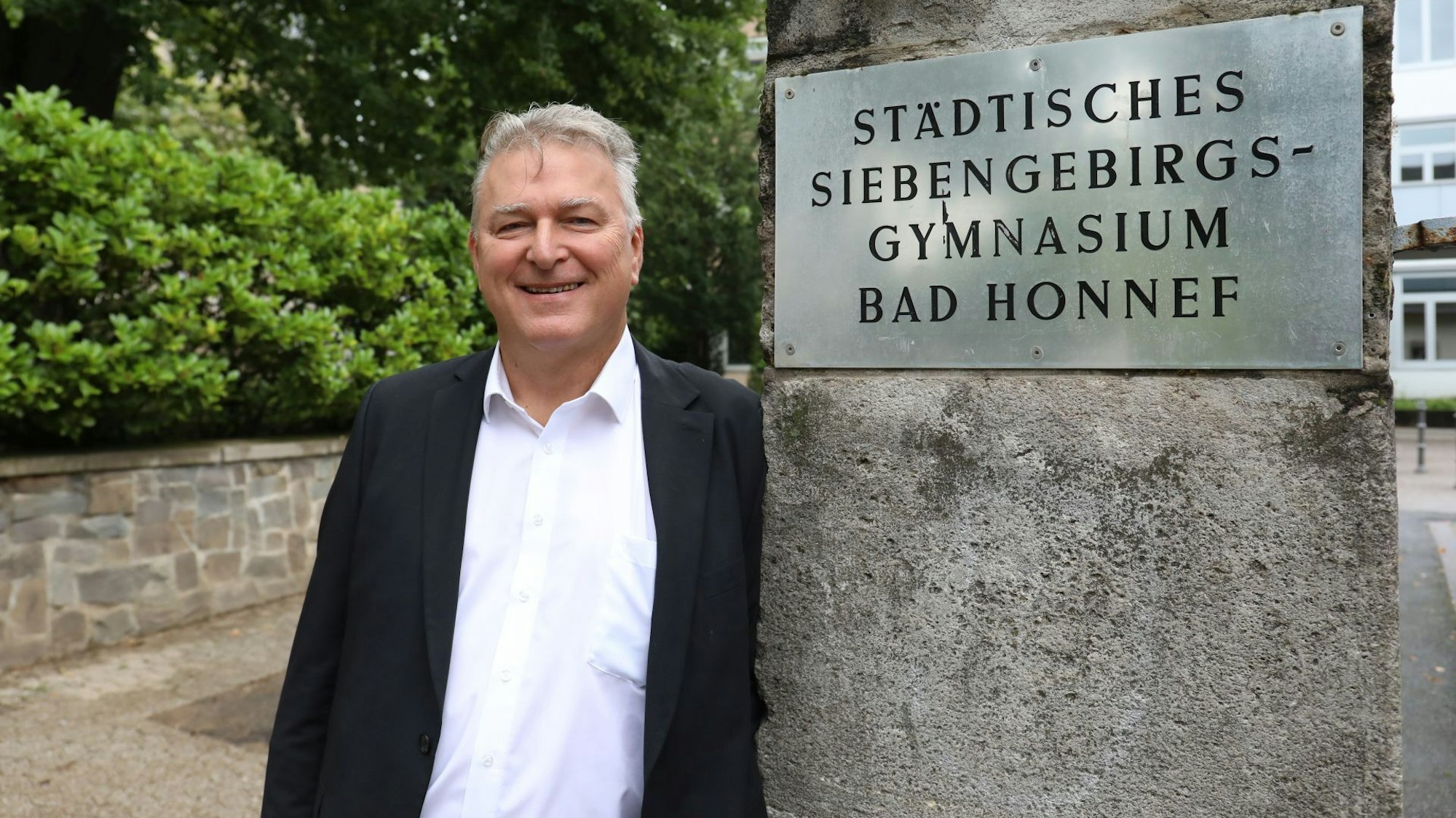 Ein Mann neben einem Schild mit der Aufschrift Städtisches Siebengebirgsgymnasium Bad Honnef.