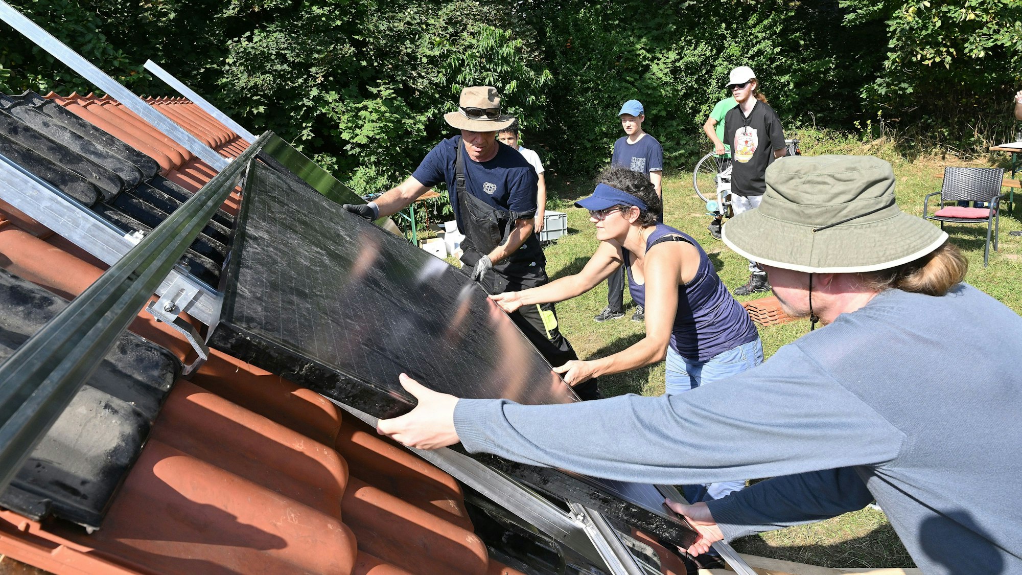 Drei Leute heben ein Paneel auf die Halterung.