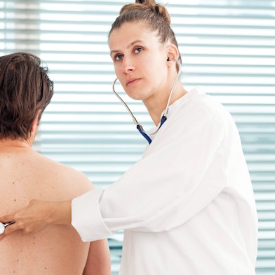 Eine Ärztin hört einen Patienten ab.