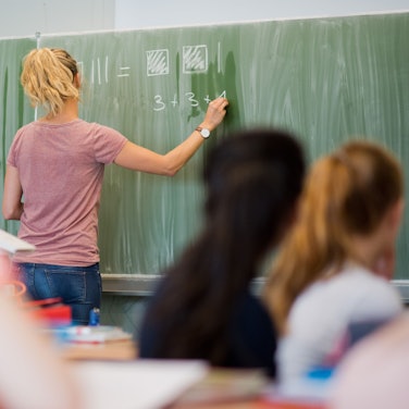 Eine Lehrerin schreibt an der Tafel.