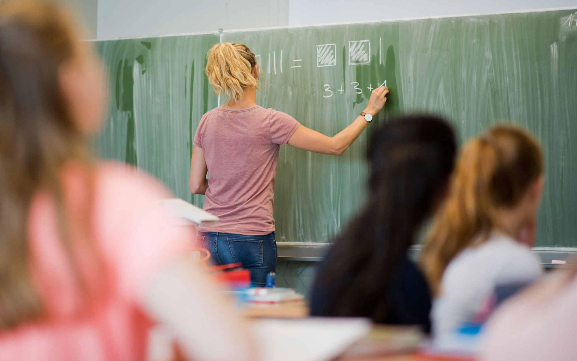 Eine Lehrerin schreibt an der Tafel.