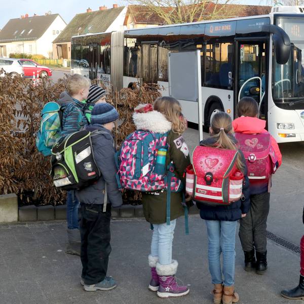 Schulkinder stehen vor einem Bus.