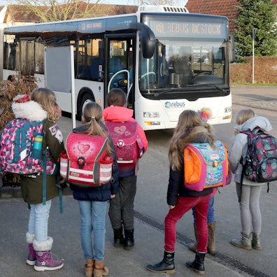 Schulkinder stehen vor einem Bus.