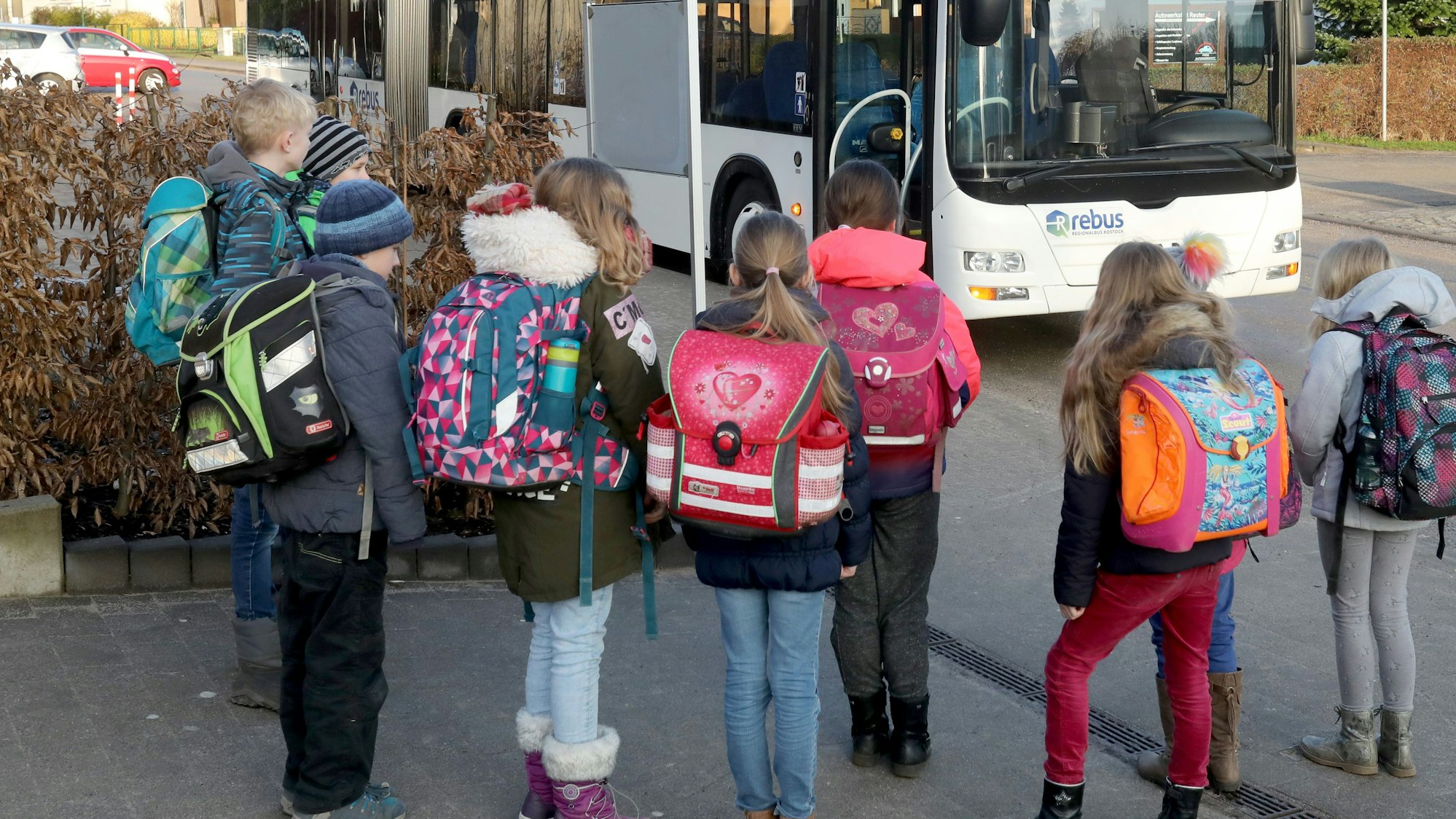Schulkinder stehen vor einem Bus.