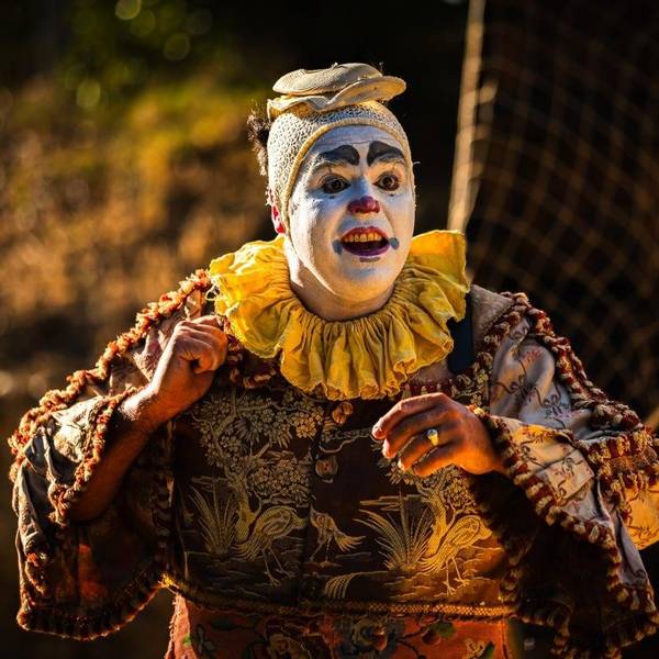 Ein Clown mit weiß geschminktem Gesicht.