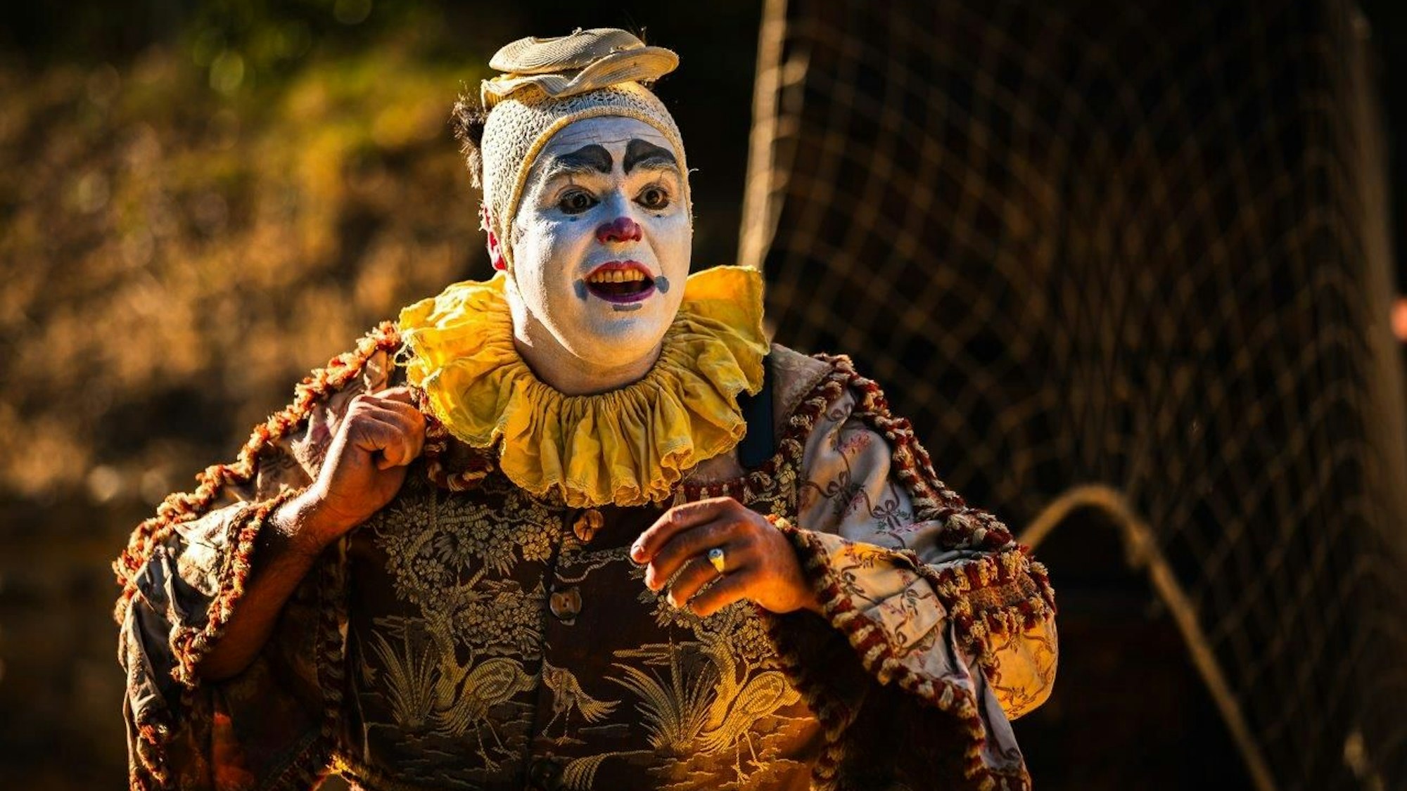 Ein Clown mit weiß geschminktem Gesicht.