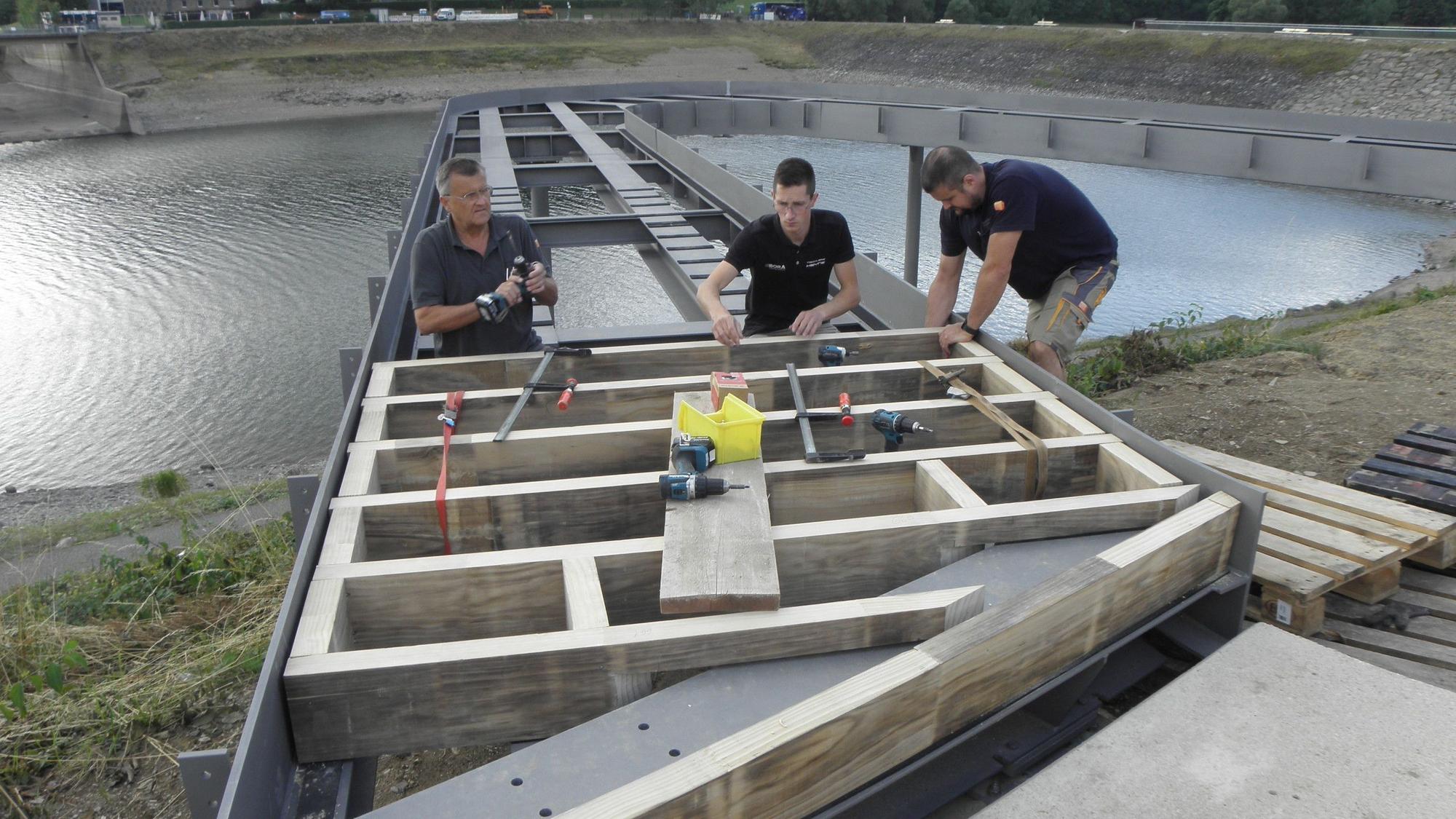 Drei Handwerker arbeiten an einem Holzgestell, das zu einem der Balkone entwickelt werden soll.