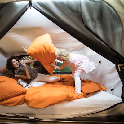 Eine Frau und ein Mädchen toben mit Kissen.