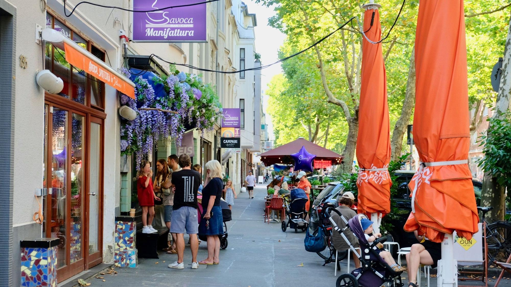 Am Fenster und im Außenbereich der Café-Bar Savoca auf dem Gottesweg sind viele Fans unterwegs.
