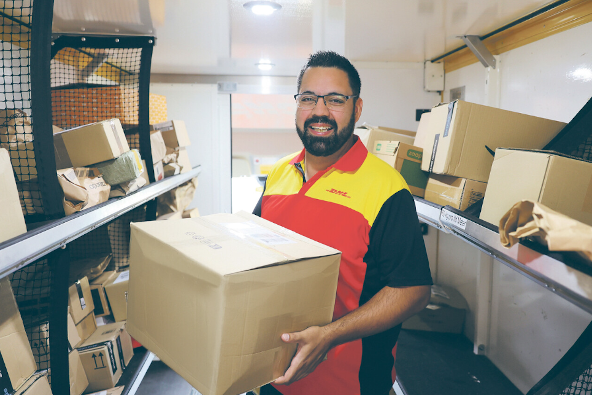DHL-Fahrer hält Paket in den Händen.