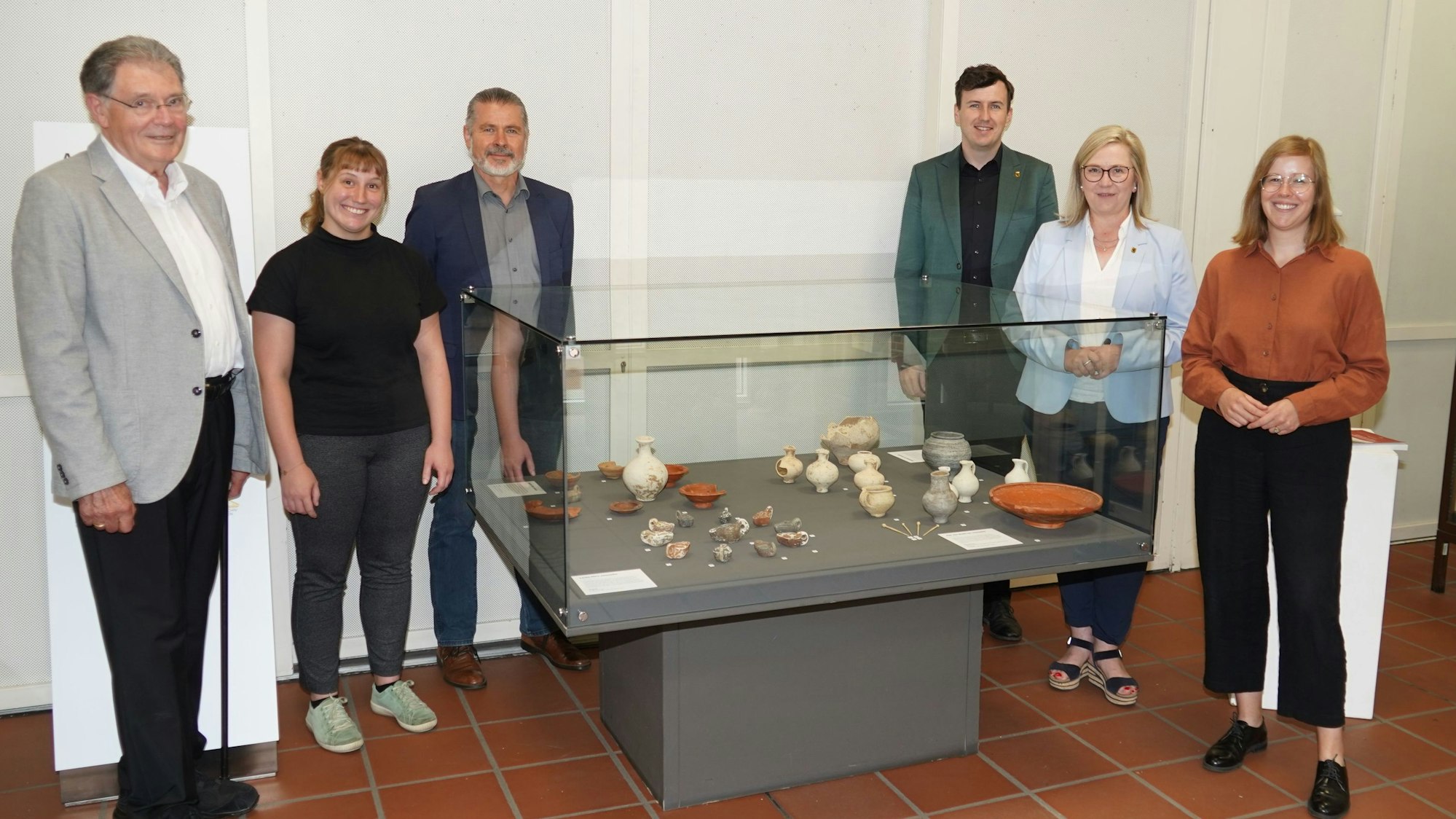 Auf dem Bild ist eine Gruppe von Männern und Frauen neben einer Ausstellungsvitrine zu sehen.