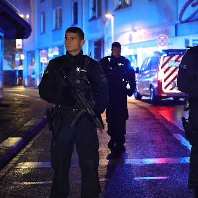 Polizei und Rettungswagen stehen in der Nacht des Anschlags in der Nähe des Fronhofs. Zwei junge Polizisten mit Maschinengewehr und ernstem Blick sind im Fokus des Bildes.