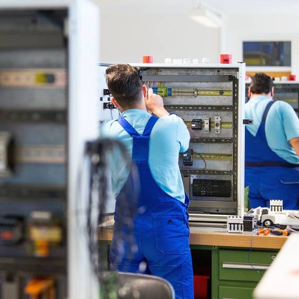 Drei junge Flüchtlinge arbeiten im Ausbildungszentrum der Siemens Professional Education an der Verdrahtung eines Schaltschranks. Foto: Monika Skolimowska/dpa-Zentralbild/dpa