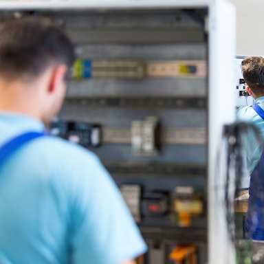 Drei junge Flüchtlinge arbeiten im Ausbildungszentrum der Siemens Professional Education an der Verdrahtung eines Schaltschranks. Foto: Monika Skolimowska/dpa-Zentralbild/dpa