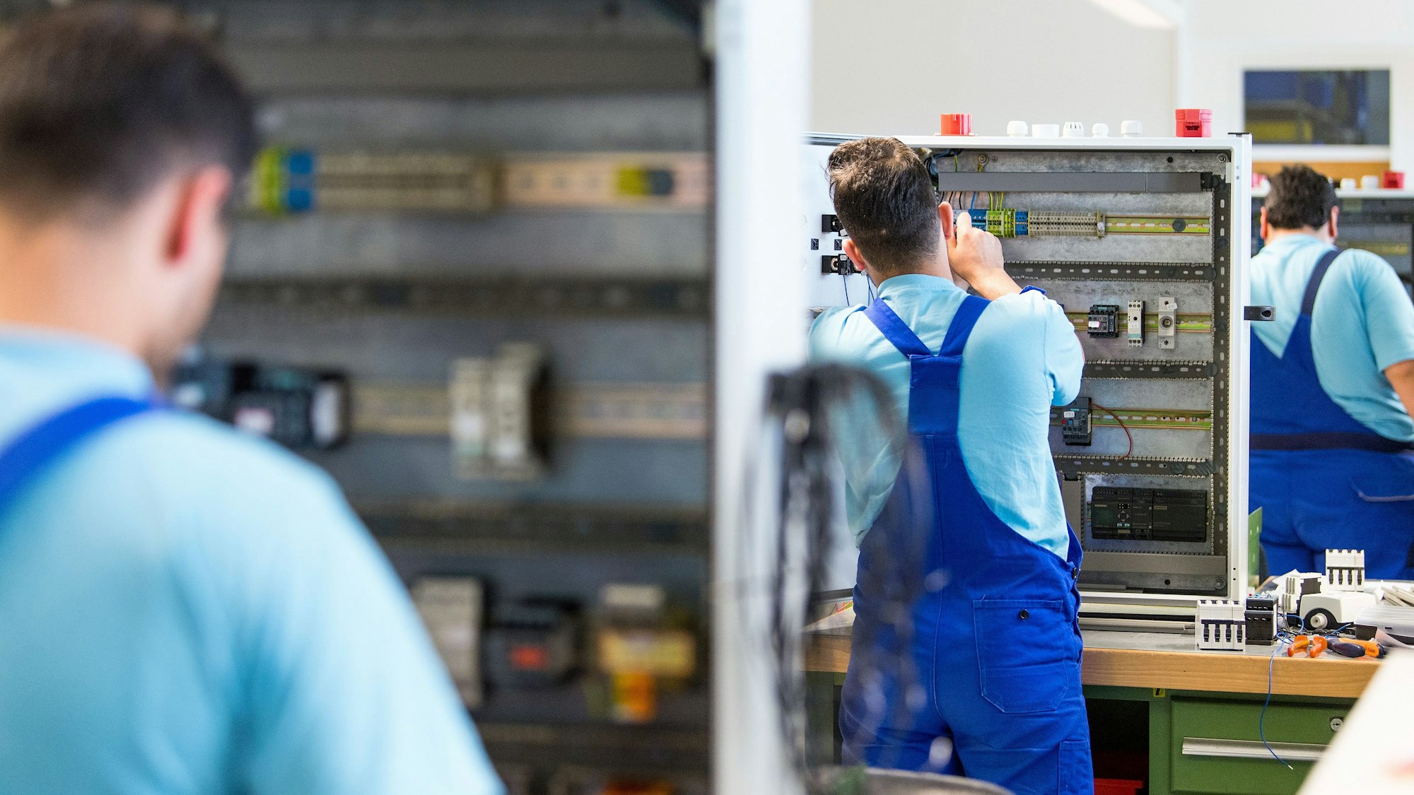 Drei junge Flüchtlinge arbeiten im Ausbildungszentrum der Siemens Professional Education an der Verdrahtung eines Schaltschranks. Foto: Monika Skolimowska/dpa-Zentralbild/dpa