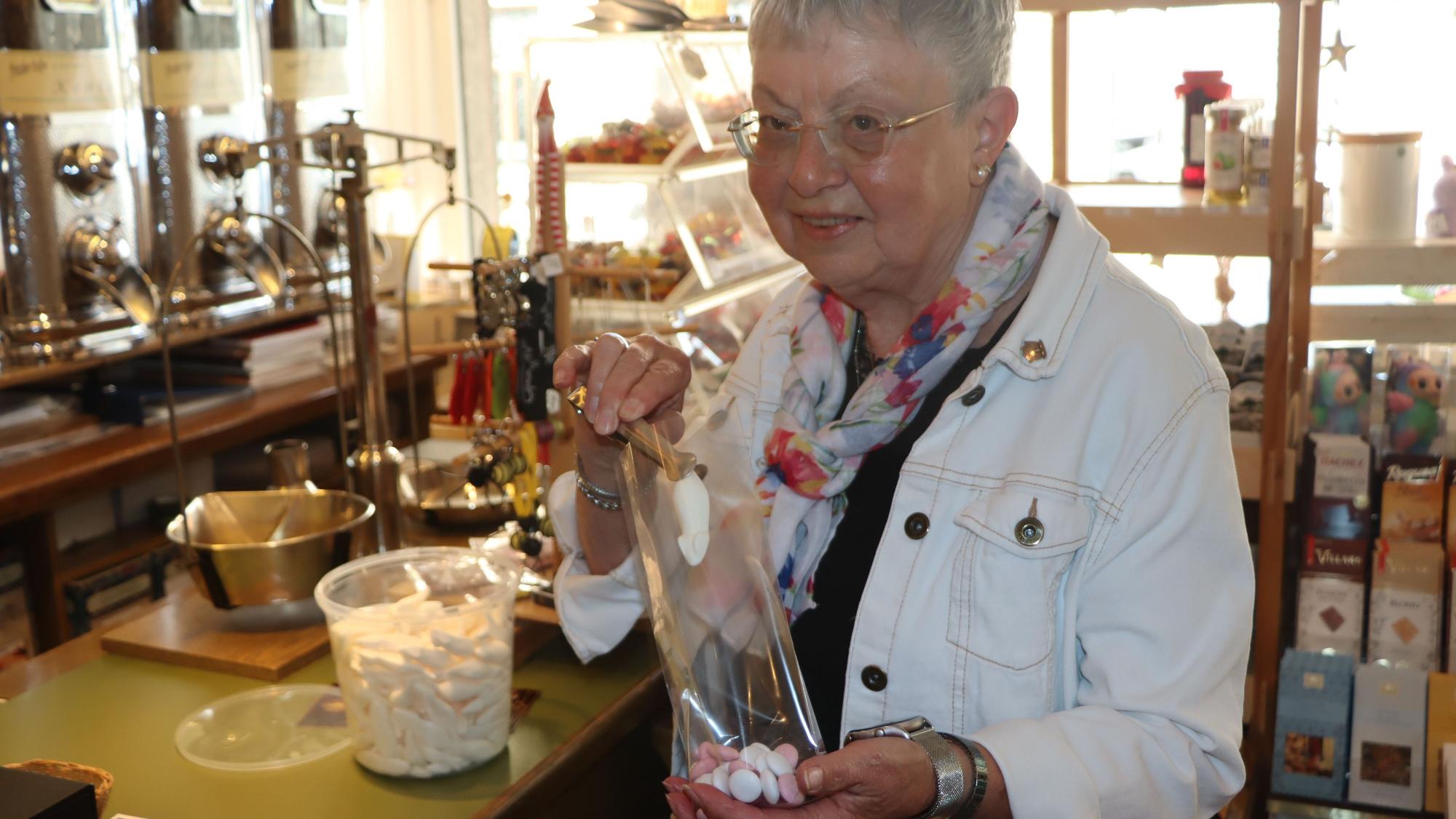 Zu sehen ist Ursula Braun, die Süßigkeiten in eine Tüte füllt.