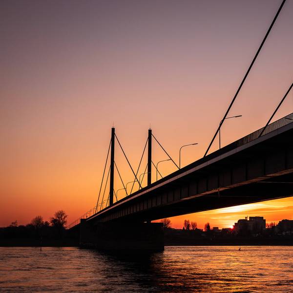 Hinter der Theodor-Heuss-Brücke in Düsseldorf geht die Sonne unter.