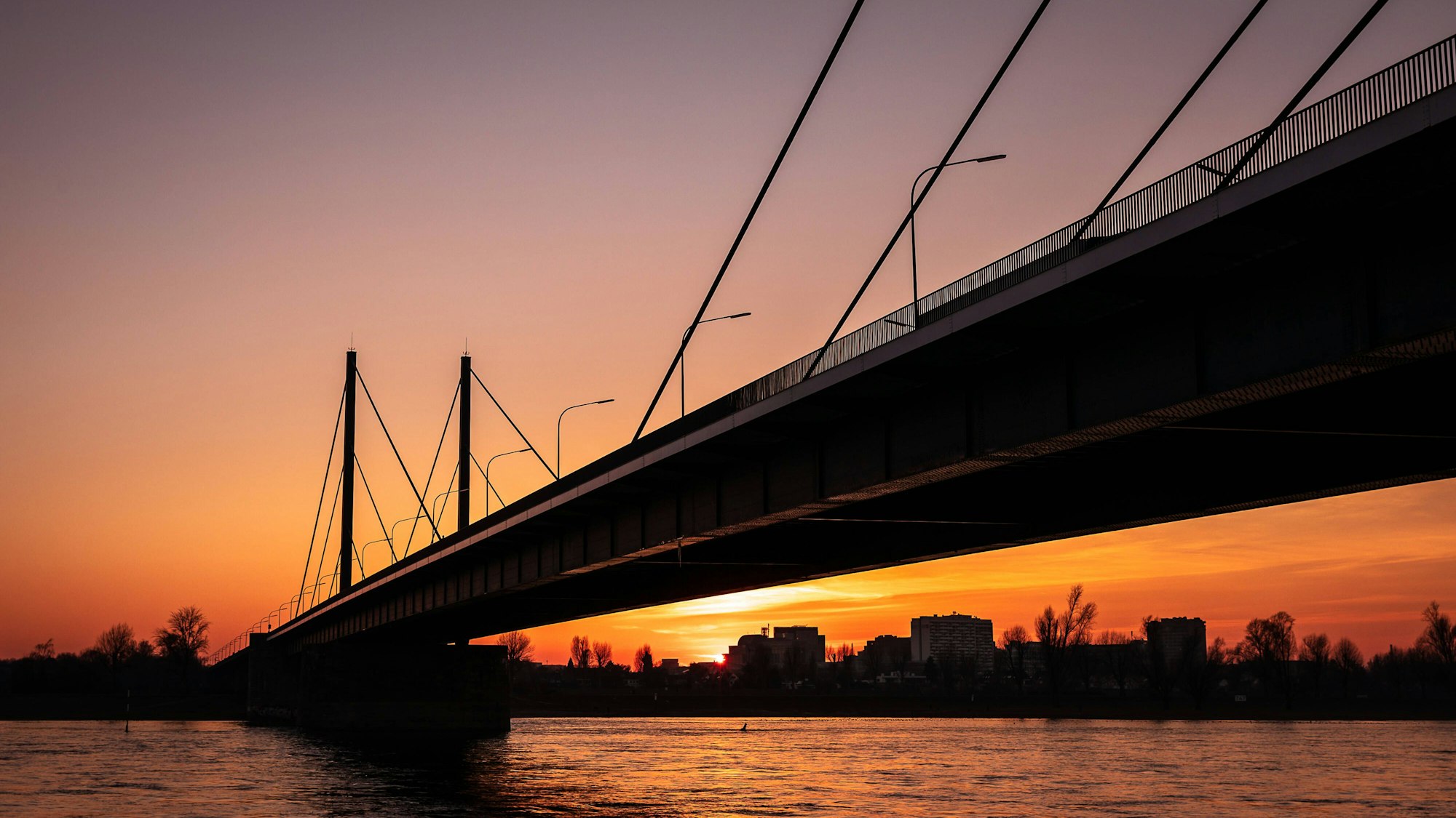 Hinter der Theodor-Heuss-Brücke in Düsseldorf geht die Sonne unter.