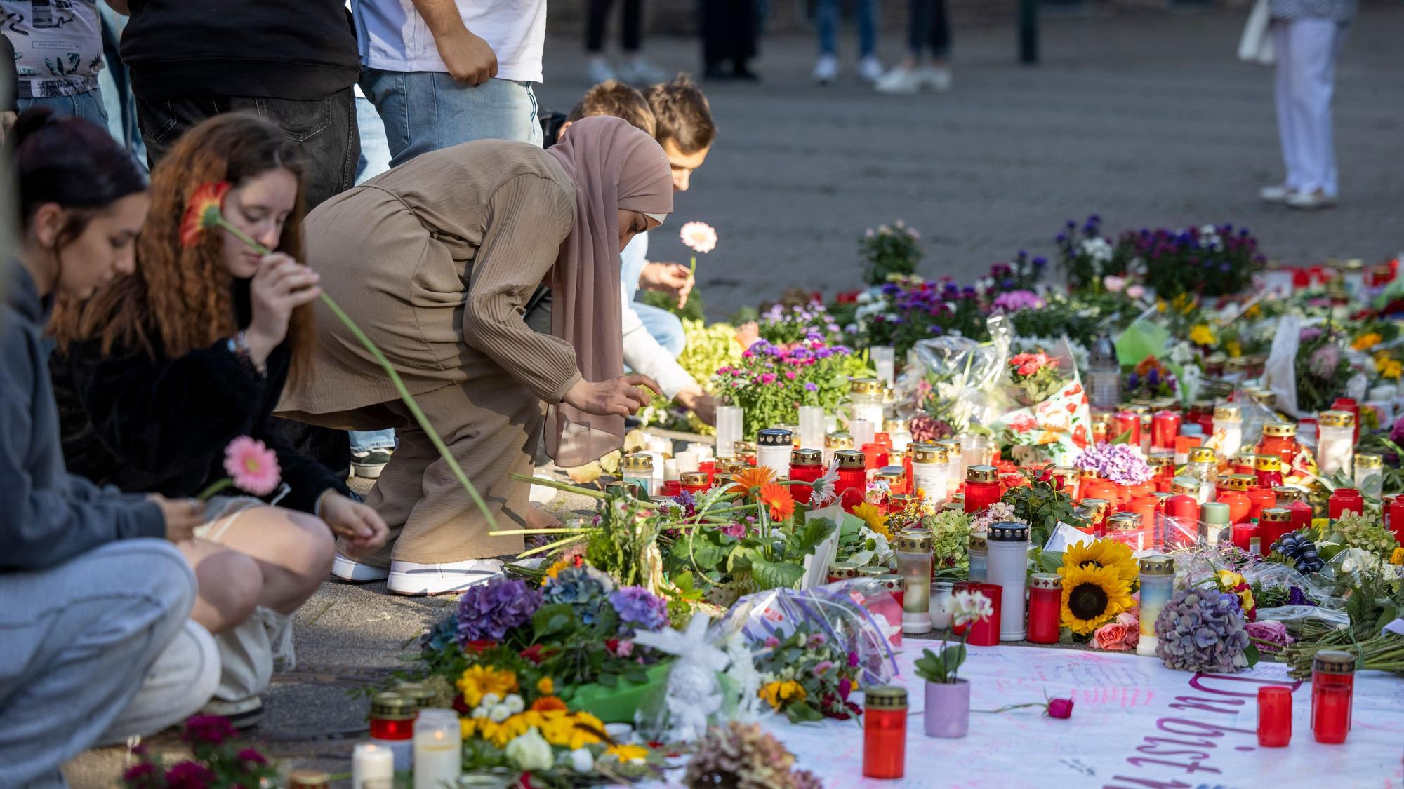 Menschen legen in der Nähe des Tatorts Blumen und Kerzen zum Gedenken der Opfer nieder.