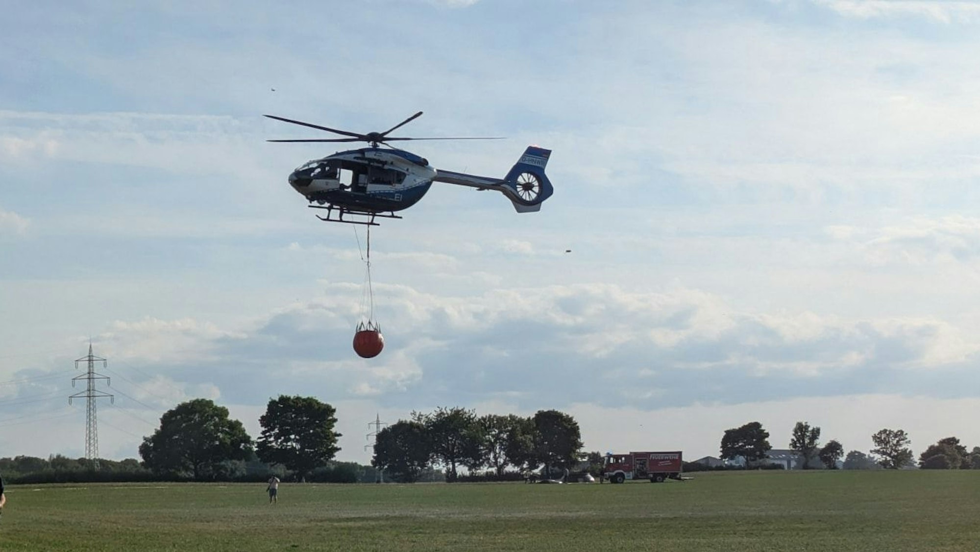 Das Foto zeigt einen Hubschrauber mit einem Löschwasser-Außenlastbehälter.