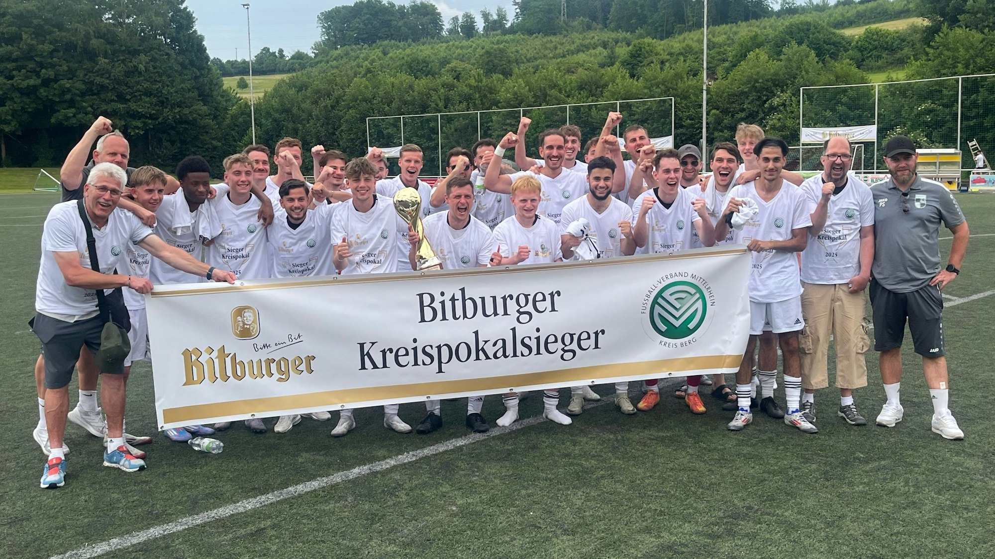 Die Fußballer des FV Wiehl feiern hinter einem Transparent den Kreismeistertitel.