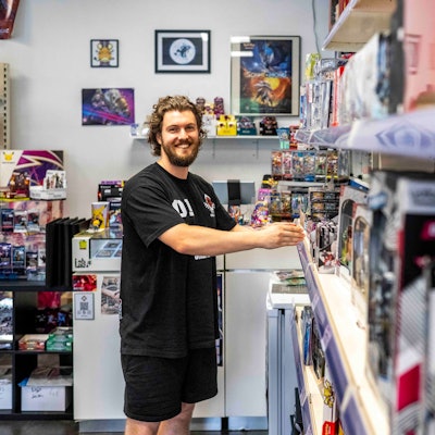 Robin Düren steht vor einem Regal, das mit Spielen gefüllt ist.