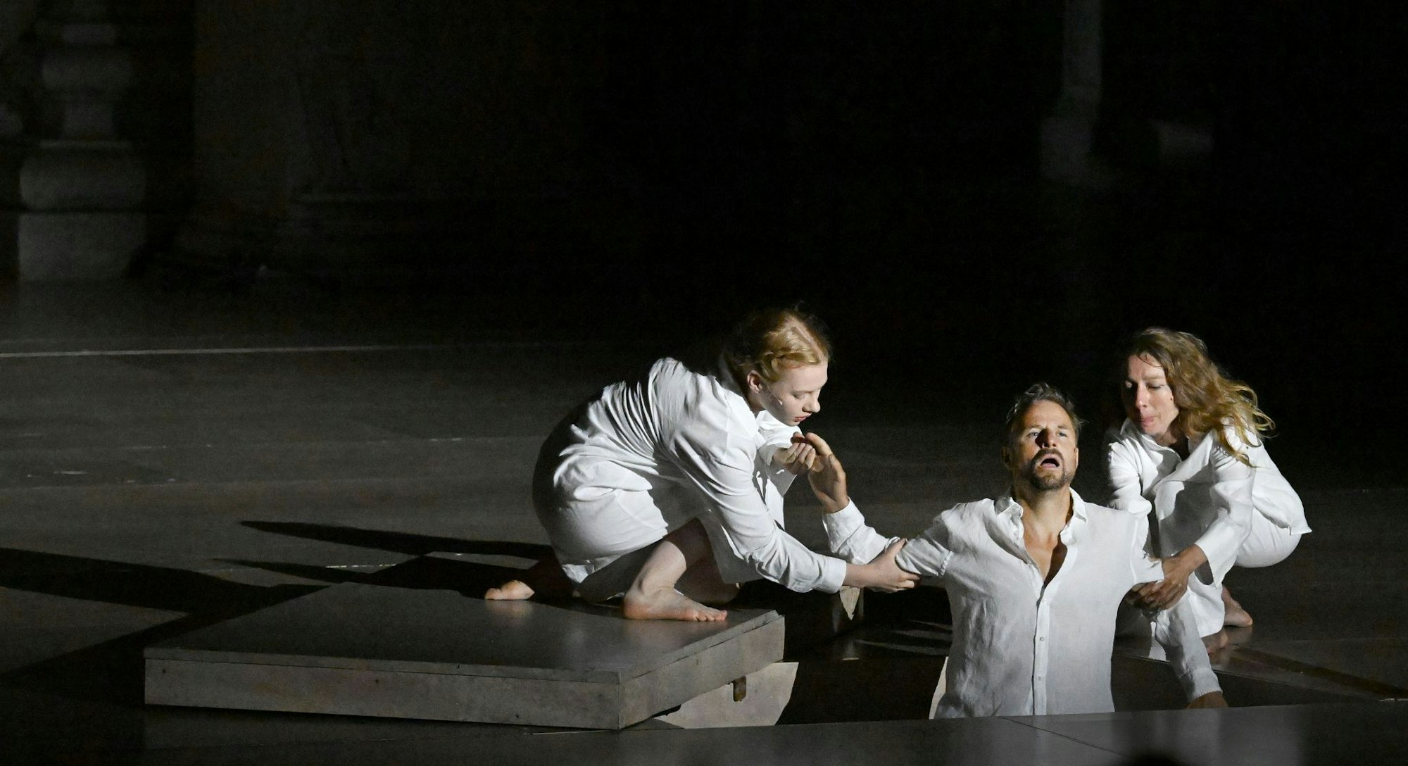 Der Jedermann (Philipp Hochmair) im Juli 2025 in seinem Grab - gehalten vom Glauben (Regine Zimmermann) und seinen Werken (Kathleen Morgeneyer). (Archivbild)