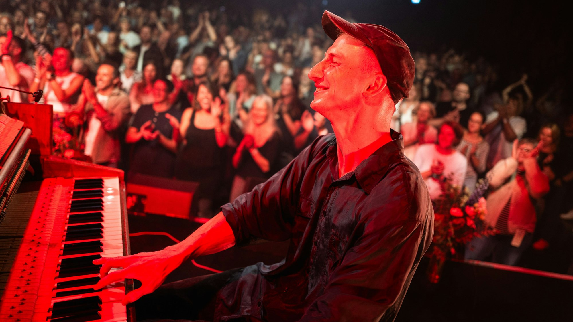 Thelonius Herrmann, besser bekannt als Stadtgeklimper, sitzt strahlend am Klavier. Im Hintergrund klatschen Menschen.