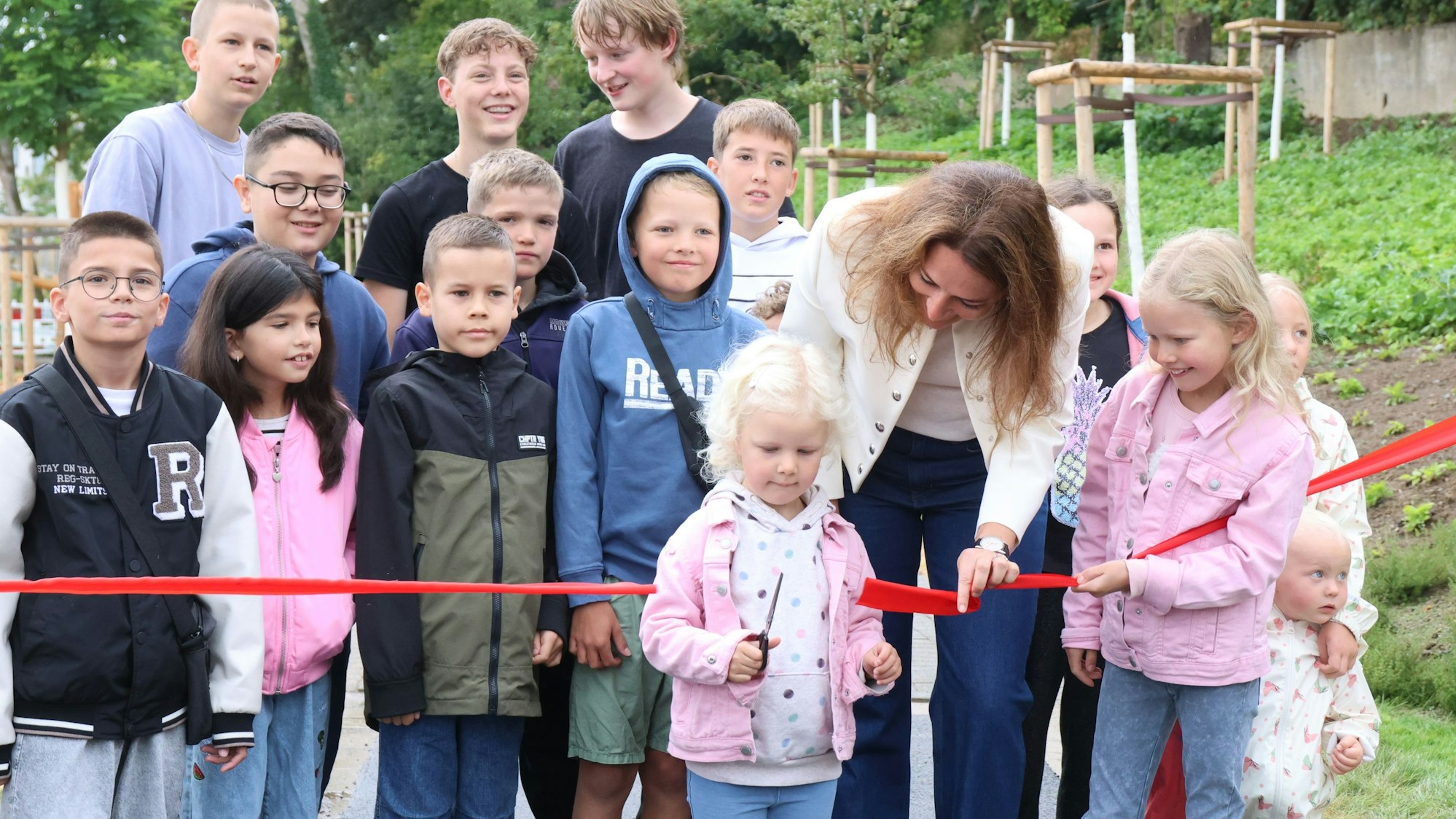 Eine Frau durchtrennt zusammen mit Kindern ein Absperrband.