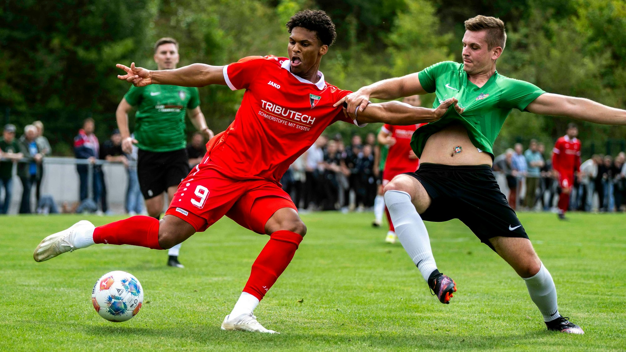 Zwei Fußballer im Zweikampf: Einer zieht den anderen am Trikot, der andere den anderen am Arm.