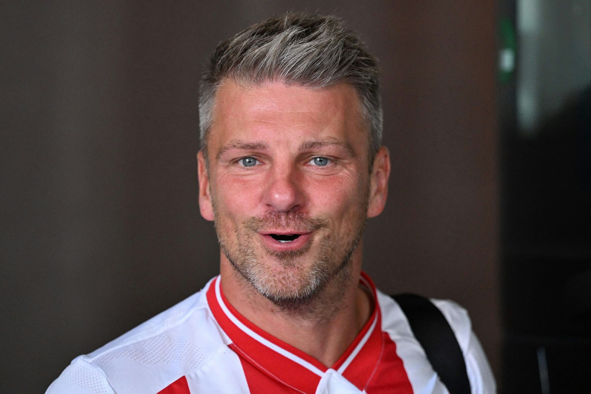Lukas Kwasniok trugt schon bei der Ankunft in Mainz ein FC-Trikot.