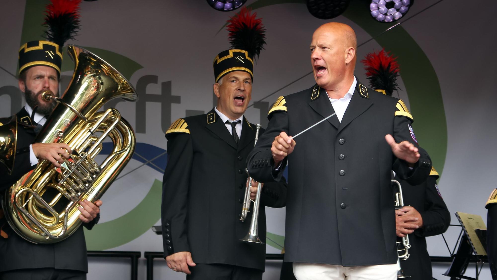 Das Foto zeigt Landrat Frank Rock, der in Uniformjacke auf der Bühne die Bergmannskapelle dirigiert.