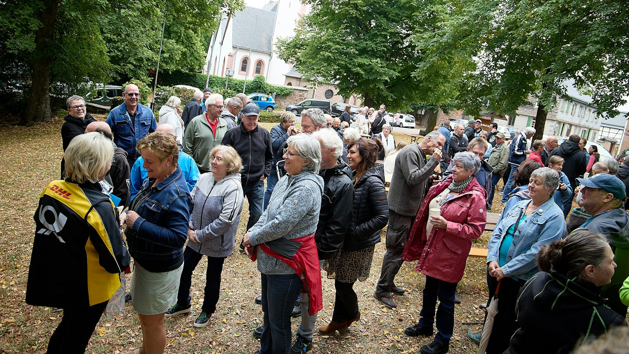 Die Postbotin steht links, vor ihr eine Schlange von Menschen, die sich bedanken wollen.