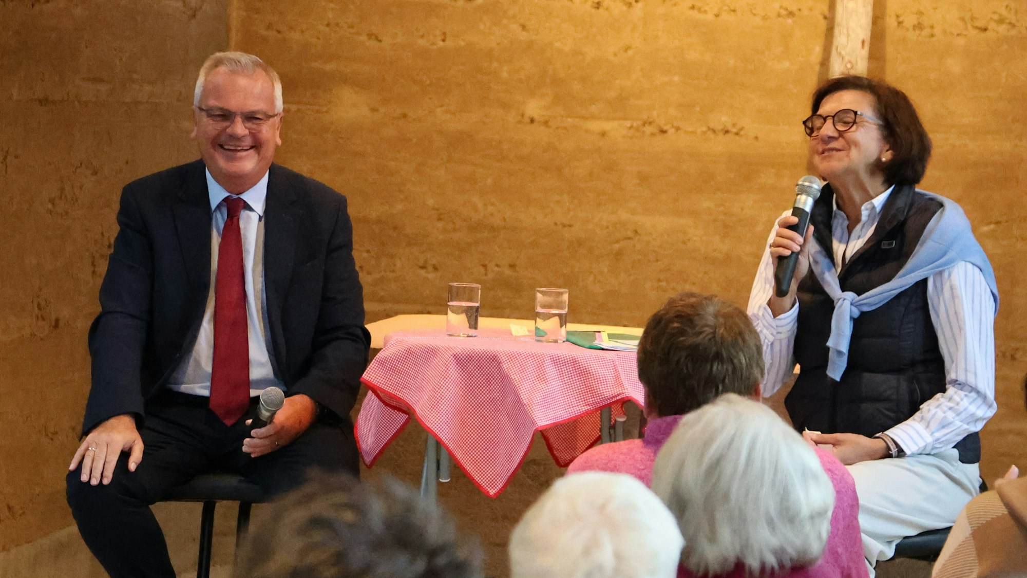 Jürgen Becker und Marianne Komp sitzen an einem tisch auf der Bühne.