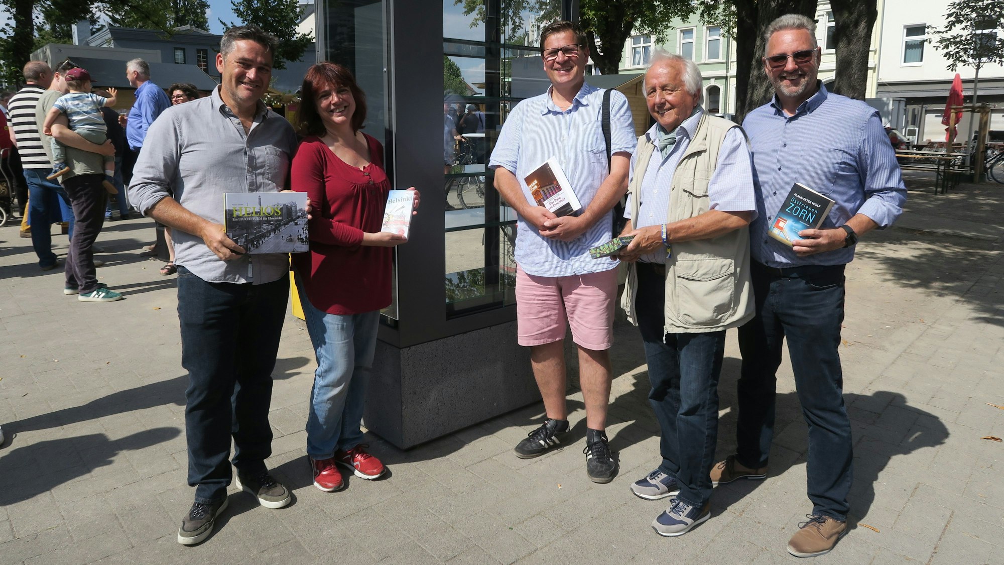Fünf Menschen stehen links und rechts von einem nagelneuen Bücherschrank.