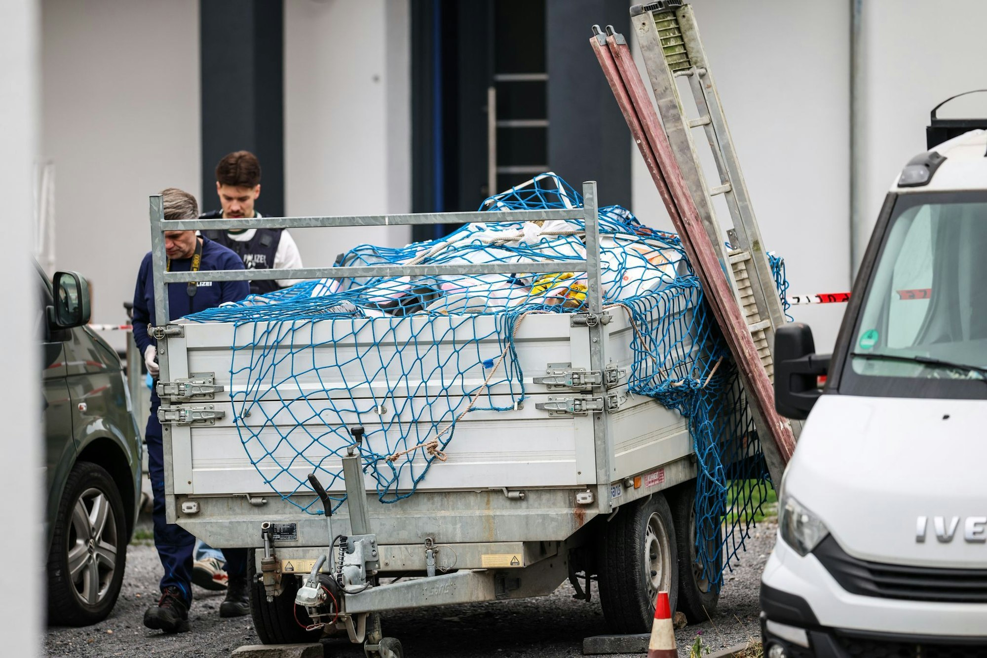 Polizeibeamte gehen neben Handwerkerfahrzeugen entlang. Hier war am vergangenen Freitag ein Handwerker erschossen worden. (Archivbild)
