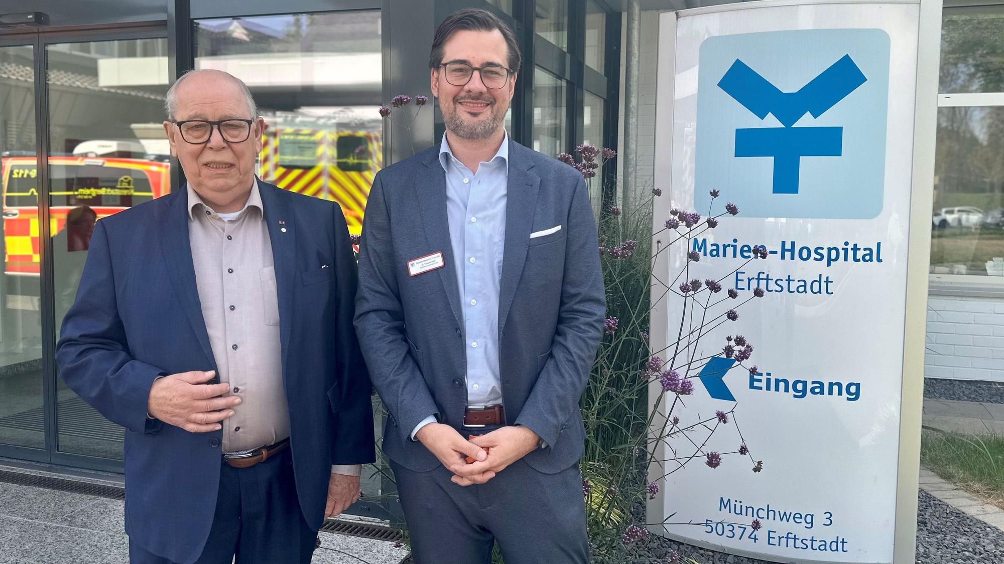 Zwei Männer stehen vor dem Eingang eines Krankenhauses.