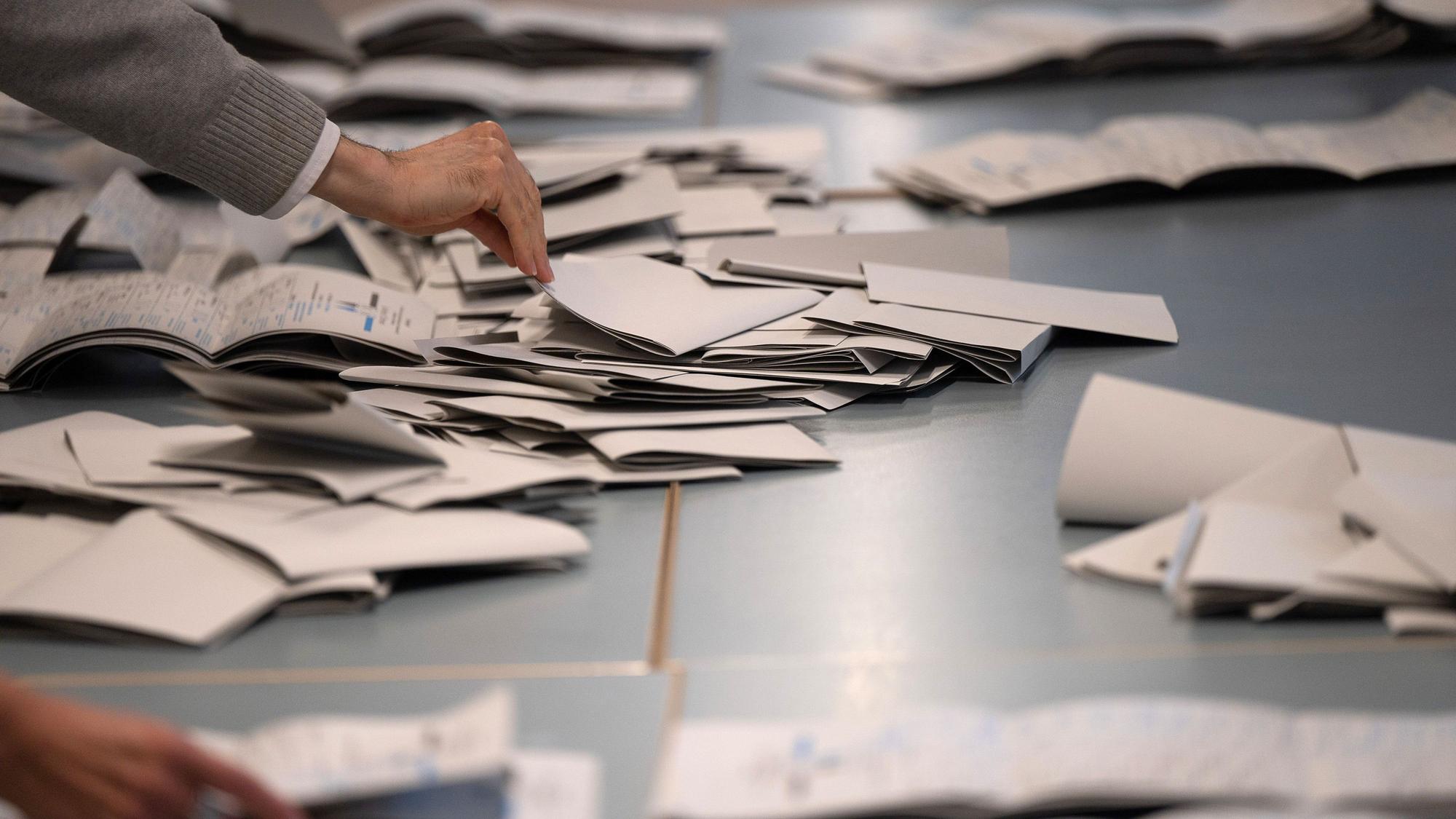 Symbolbild: Wahlhelfer und Wahlhelferinnen zählen in einem Wahllokal Stimmzettel.