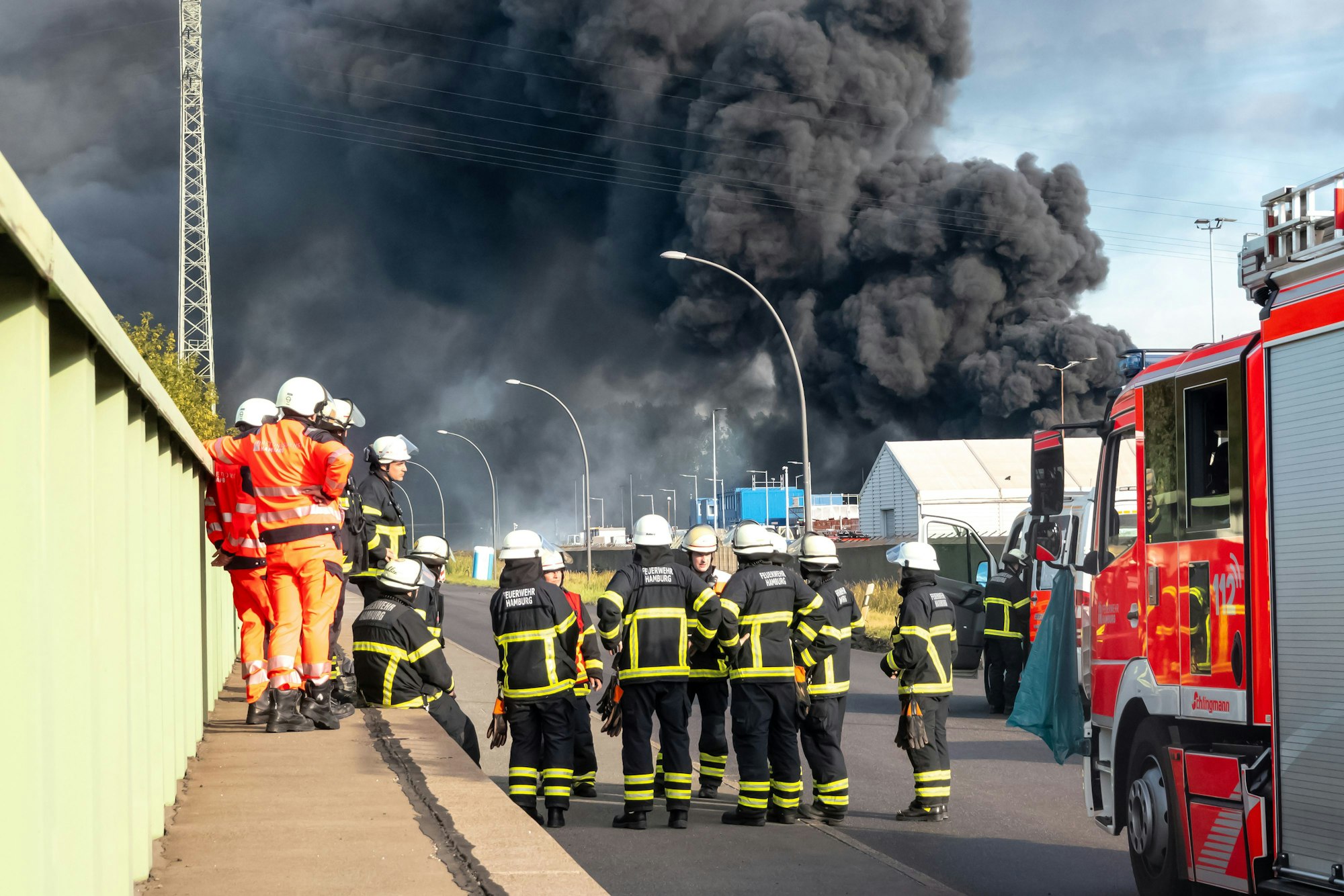 Einsatzkräfte der unterstützenden Flughafenfeuerwehr bereiten sich während eines Großbrandes auf ihrem Einsatz vor. Nachdem in einer Lagerhalle in einem Hamburger Gewerbegebiet ein Feuer ausbrach, kam es zu mehreren Explosionen. Foto: Bodo Marks/dpa