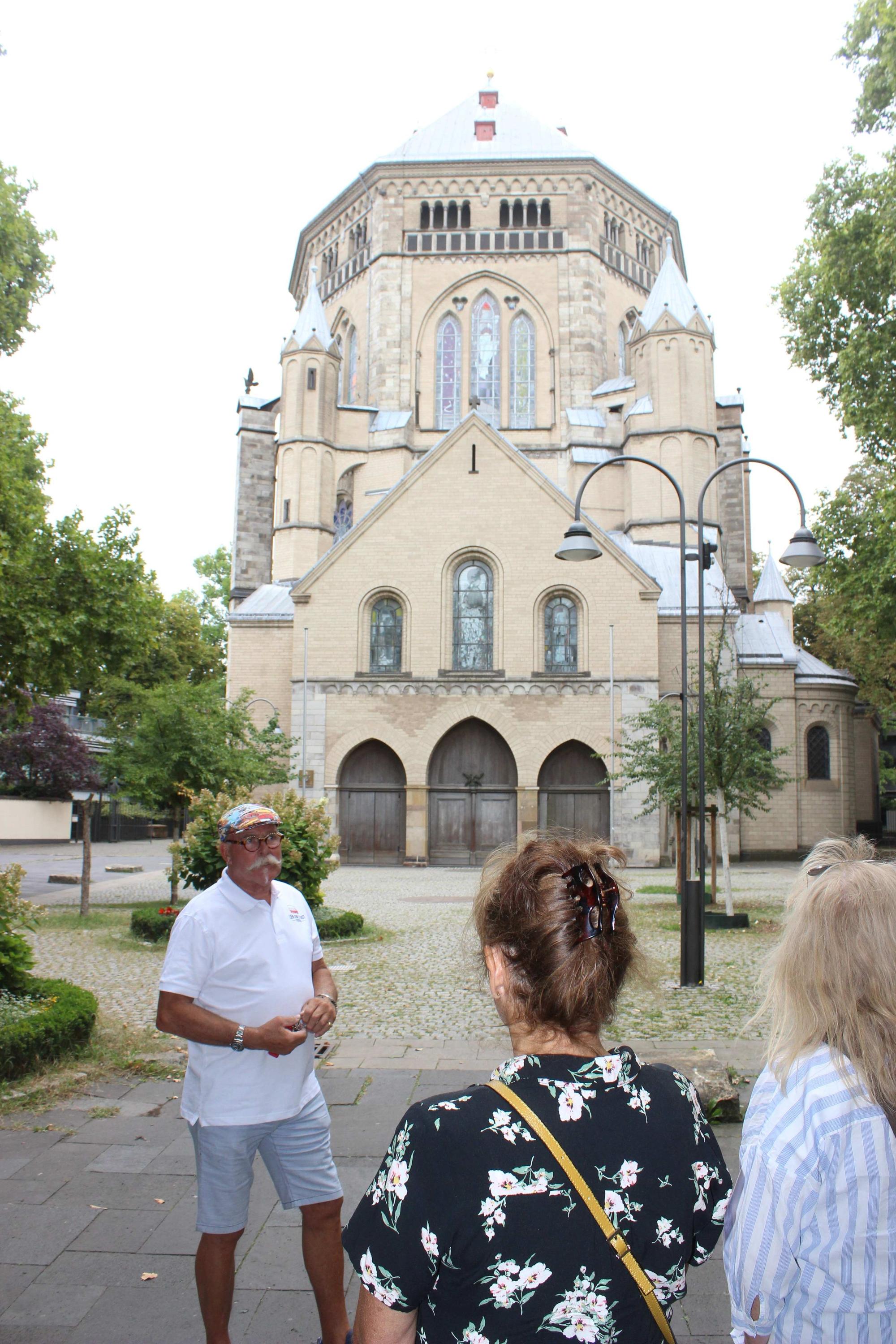 Zwischenstopp an der romanischen Kirche St. Gereon. Guide Arno Bös erklärt seinen Gästen die Stadt.