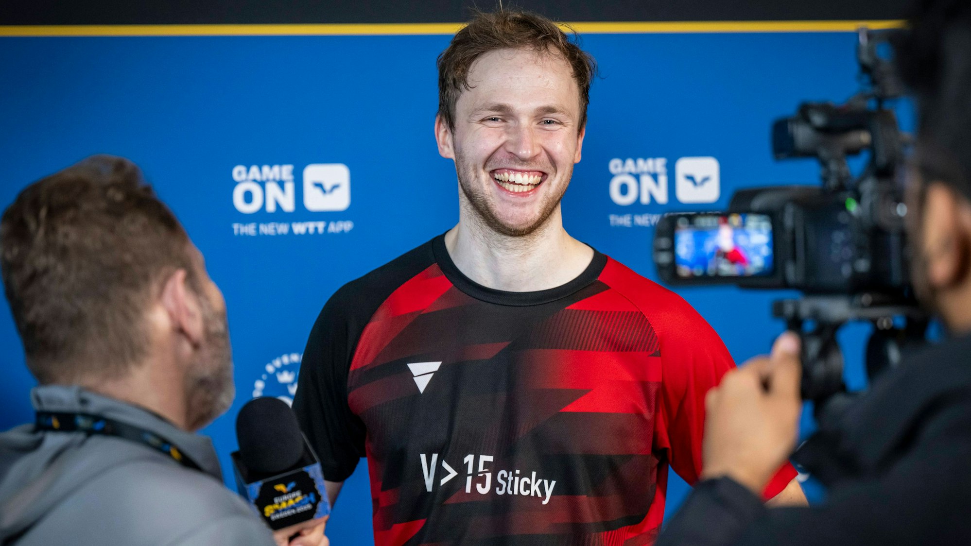 Benedikt Duda lacht bei der Pressekonferenz in die Kamera.