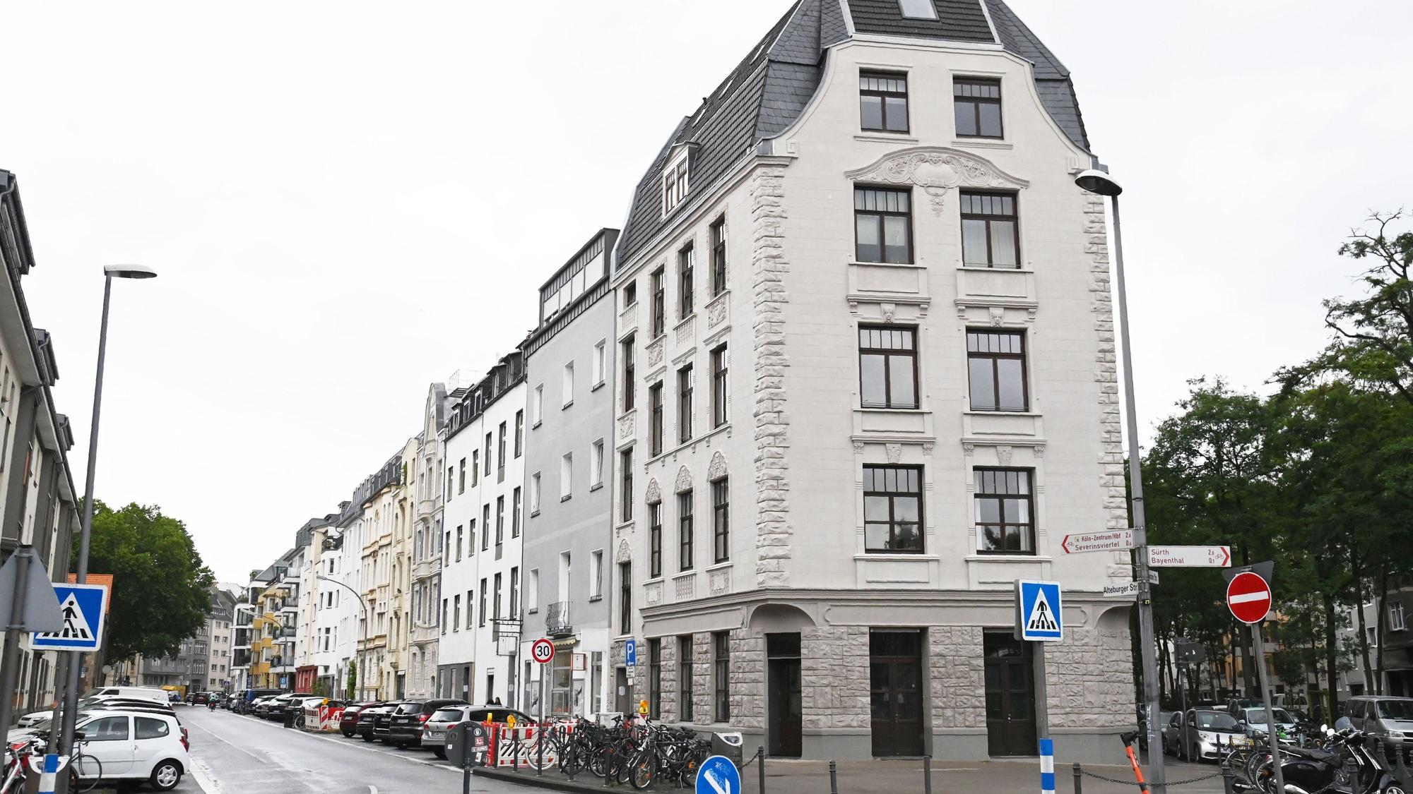 An einer Altbau-gesäumten Straße parken zahlreiche Autos.