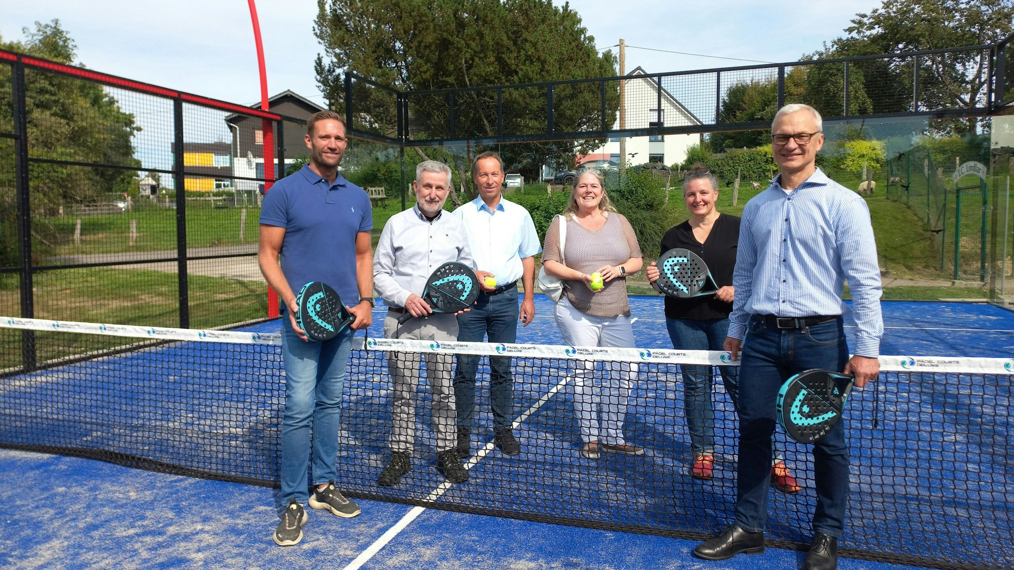 Eine Gruppe von Menschen steht auf einem Spielfeld für Padle-Tennis
