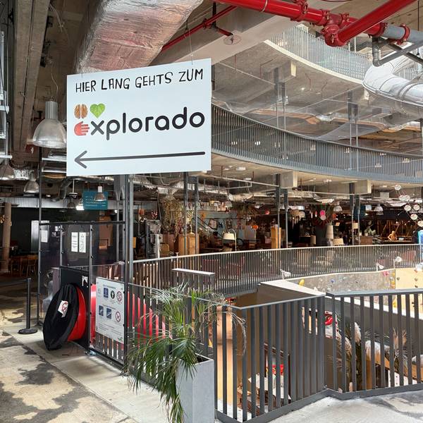 Ein Hinweisschild in einer Mall. „Hier lang geht's zum Explorado“ steht darauf.