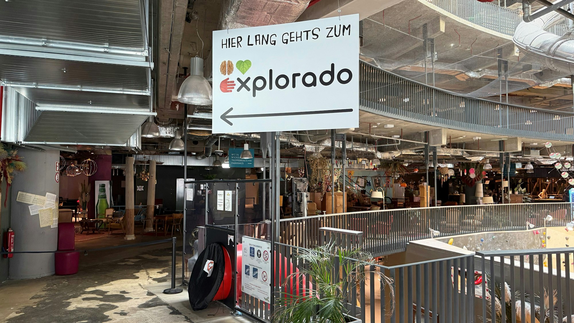 Ein Hinweisschild in einer Mall. „Hier lang geht's zum Explorado“ steht darauf.