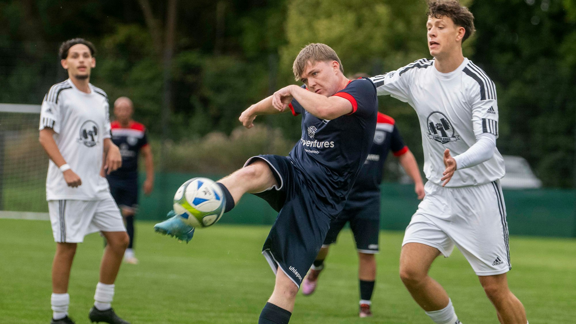 Ein Fußballer beim Torschuss, der Gegenspieler, der sich von hinten nähert, kommt zu spät.