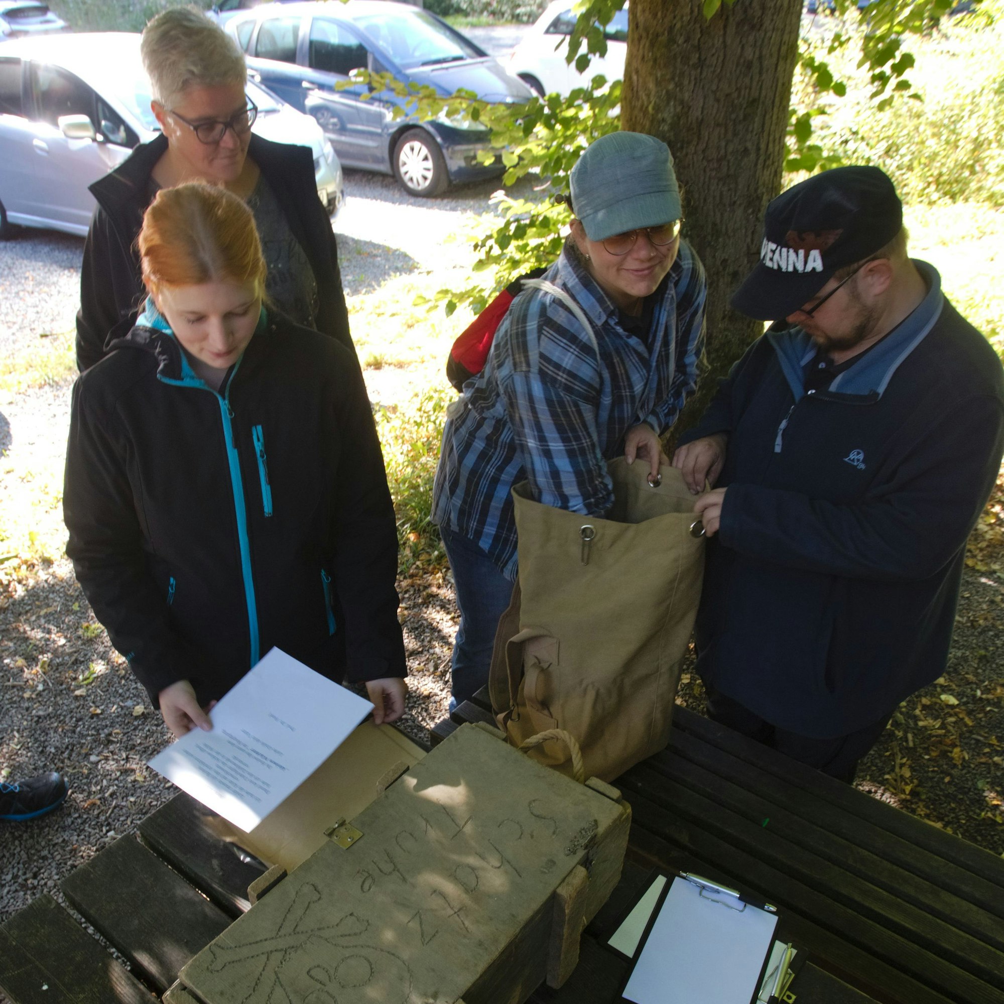 Eine Gruppe steht im Rahmen einer Rätsel-Tour um eine verschlossene Kiste herum.
